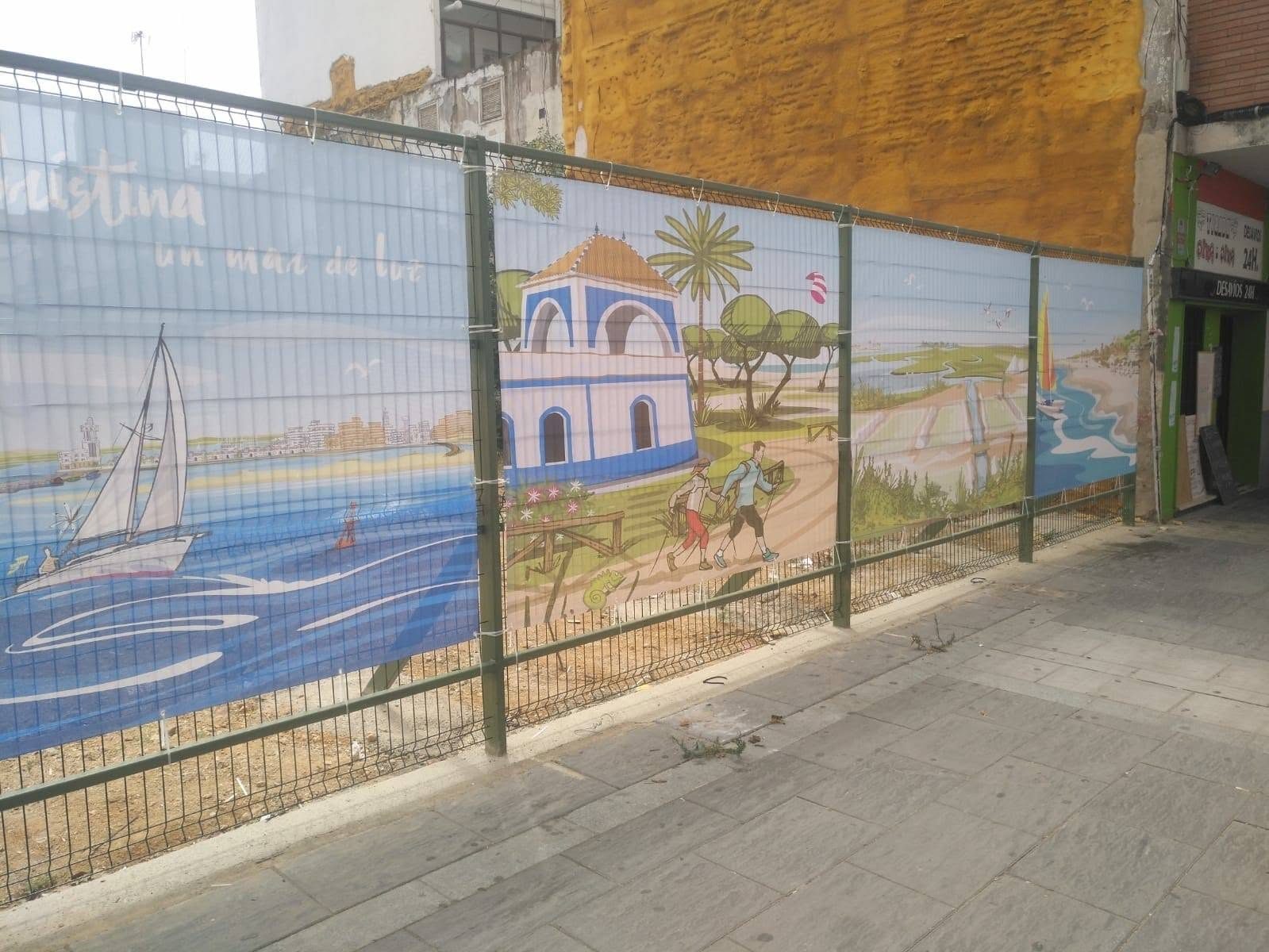 Vallado metálico cubierto con una lona ilustrada de playa y barcos