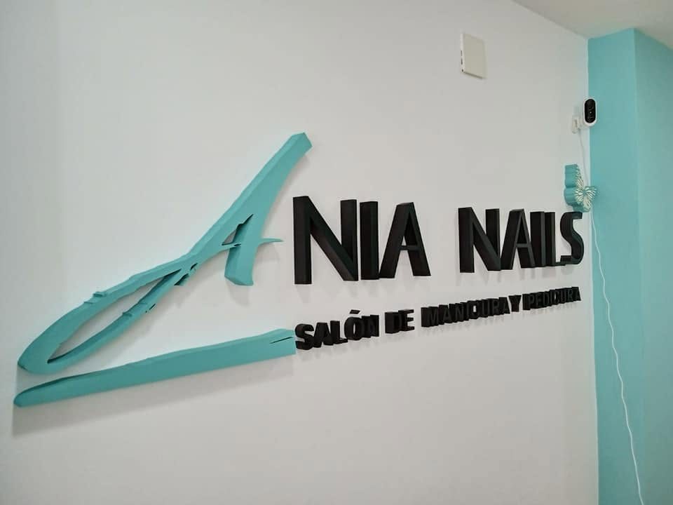 Logotipo en relieve turquesa y negro en una pared blanca