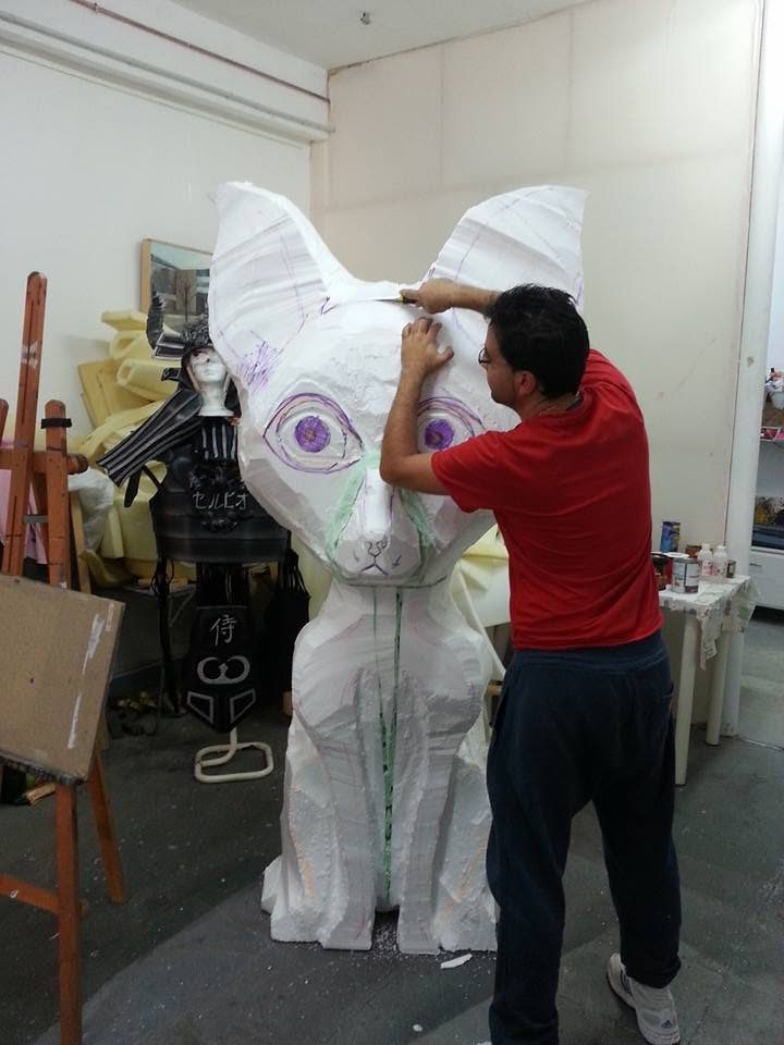 Persona trabajando en una figura blanca de gran tamaño en el taller